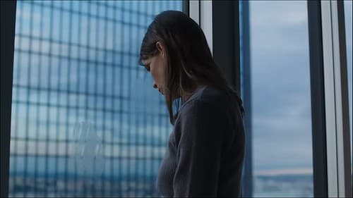 Film still: a woman at a high window, the towers reflected in the glass